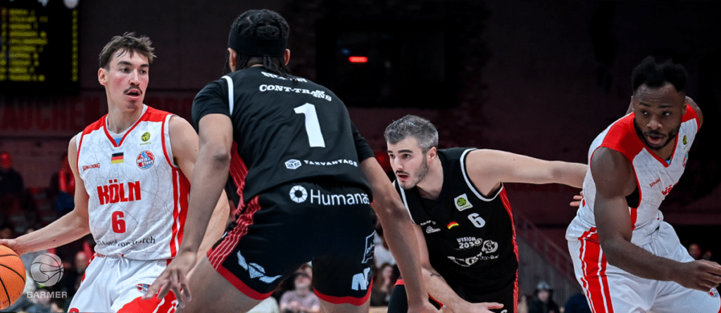 Basketballspiel zwischen RheinStars Köln in Weiß-Rot und Team in Schwarz-Rot mit Spielernummern 6 und 1.
