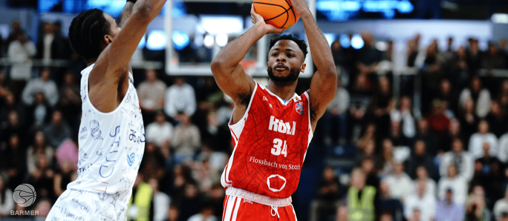 Basketballspieler der RheinStars Köln in rotem Trikot beim Wurf.