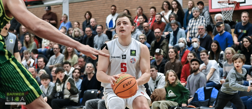 Basketballspieler der RheinStars Köln mit Nummer 5 hält Ball während Spiel vor Publikum.