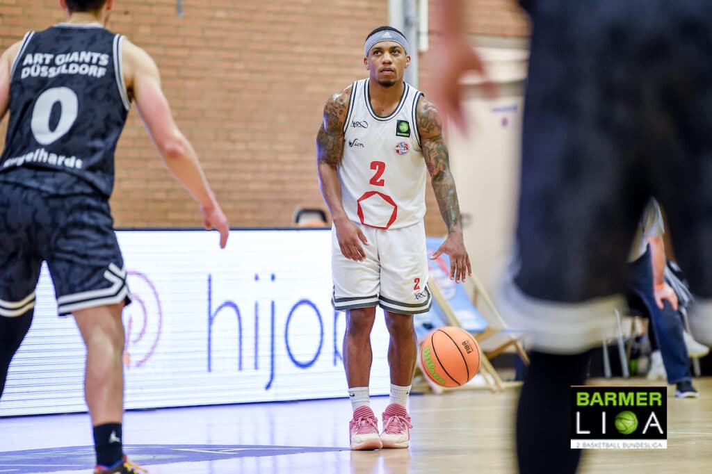 Basketballspieler der RheinStars Köln in weißem Trikot mit Nummer 2 dribbelt den Ball während eines Spiels.