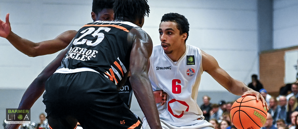 Basketballspieler der RheinStars Köln in weißem Trikot Nummer 6 dribbelt gegen Gegner in schwarzem Trikot.