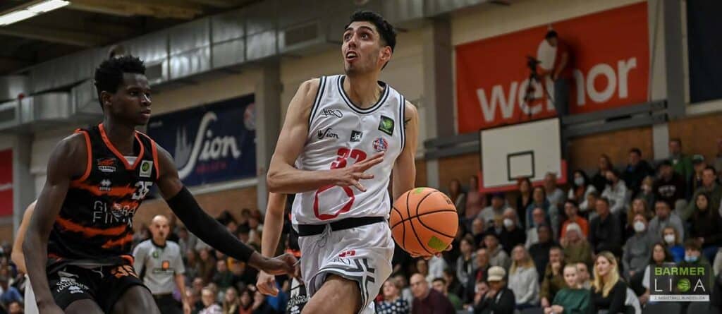 Basketballspieler der RheinStars Köln dribbelt Ball während Heimspiel vor Publikum.