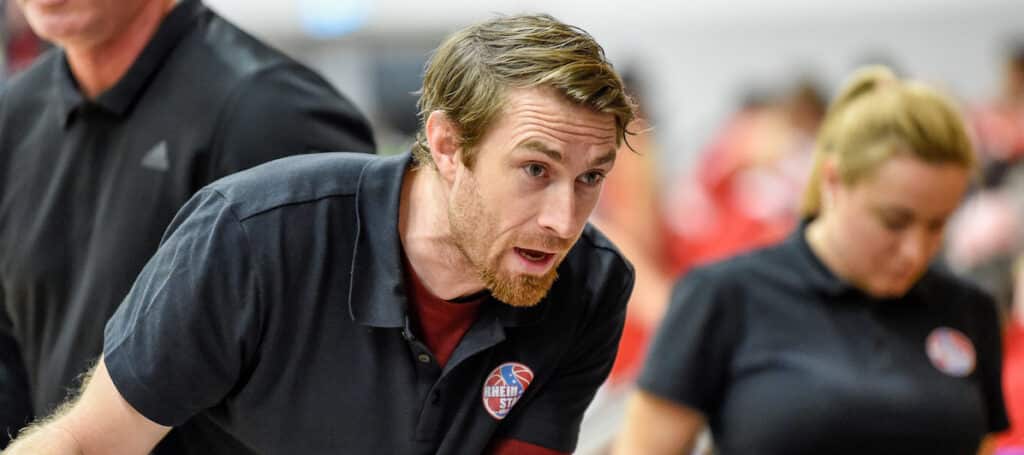 Mann in RheinStars-Köln-Polo spricht gestikulierend bei Sportveranstaltung.