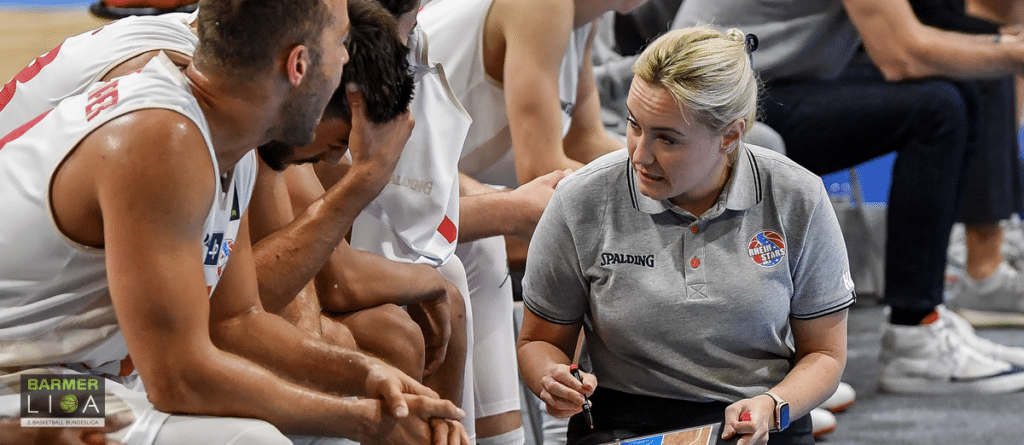 Trainerin der RheinStars Köln gibt Basketball-Spielern Anweisungen während eines Spiels.