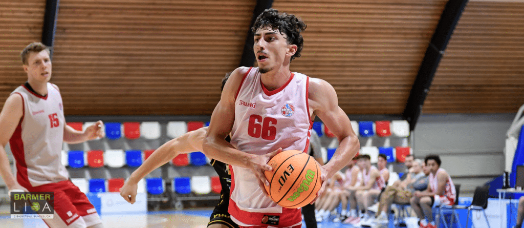 Basketballspieler der RheinStars Köln mit Nummer 66 dribbelt den Ball in der Sporthalle.