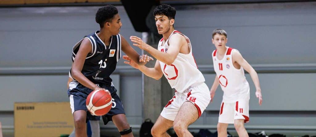 Basketballspiel der RheinStars Köln: Spieler in schwarzem Trikot mit Ball gegen Verteidiger in weißem Trikot.