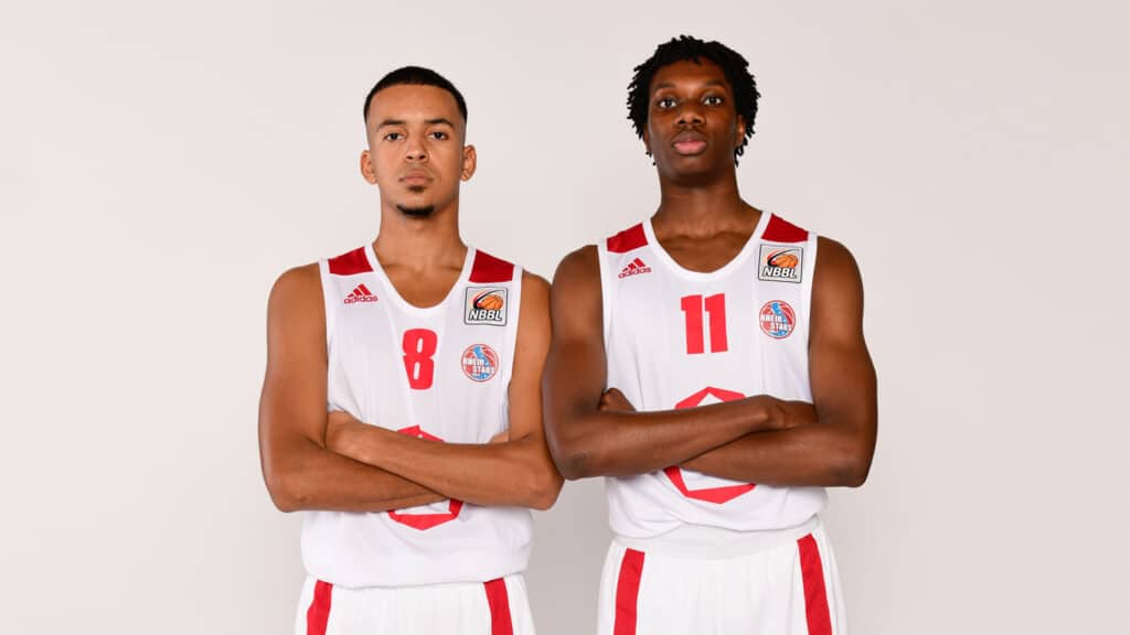 Zwei Basketballspieler der RheinStars Köln in weißen Trikots mit den Nummern 8 und 11, Arme verschränkt.