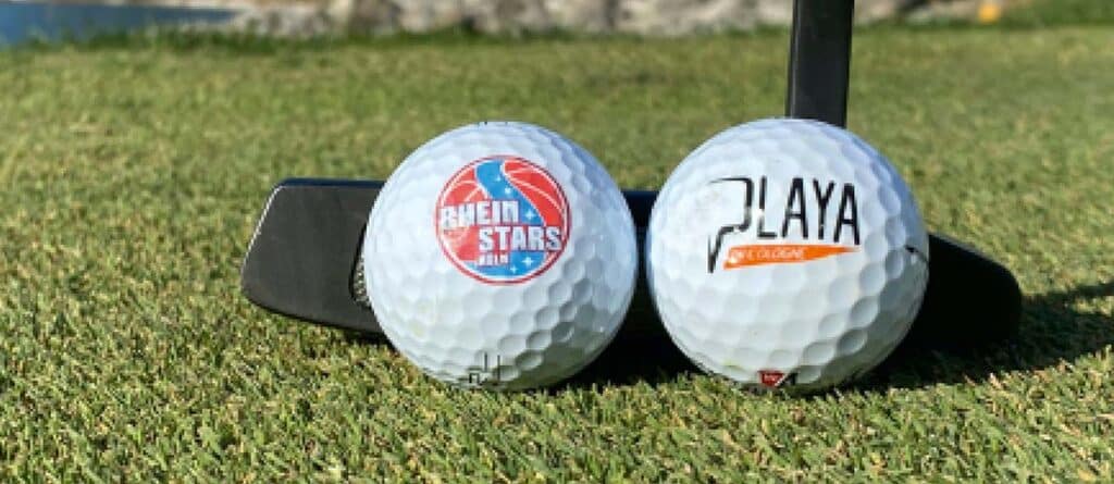 Zwei Golfbälle auf Rasen: links RheinStars Köln-Logo, rechts Playa-Schriftzug, daneben schwarzer Putter.