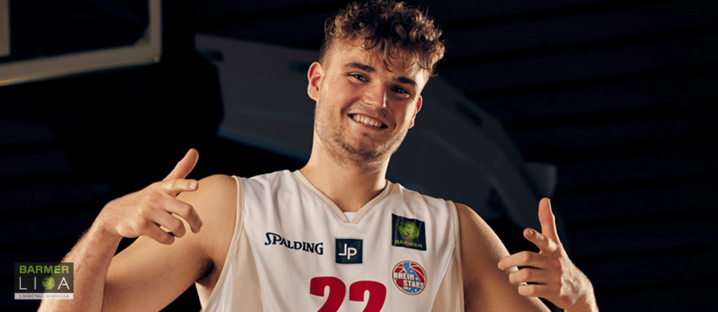 Basketballspieler der RheinStars Köln in Nummer 22 Trikot lächelt in die Kamera.