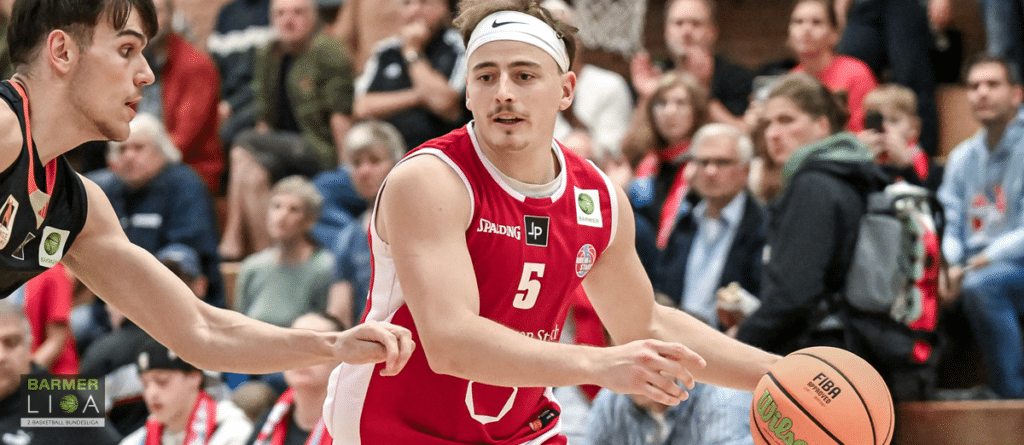 Basketballspieler der RheinStars Köln in rotem Trikot Nummer 5 dribbelt während eines Spiels.
