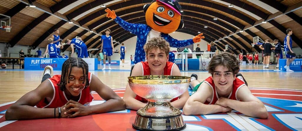 Drei Basketballspieler der RheinStars Köln posieren mit einem Pokal in einer Sporthalle.