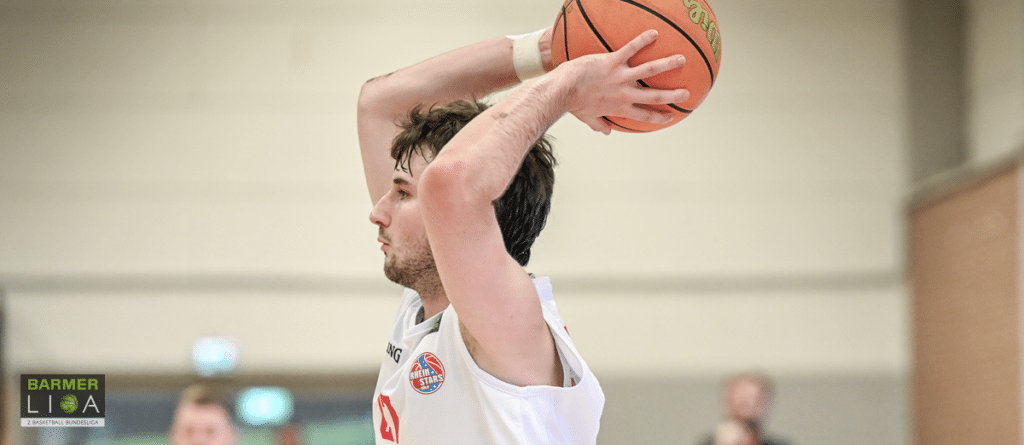 Basketballspieler der RheinStars Köln wirft Ball von oben ab.
