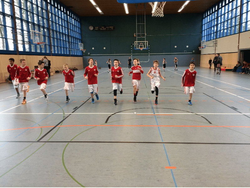 Junge Basketballspieler der RheinStars Köln trainieren in einer Sporthalle.