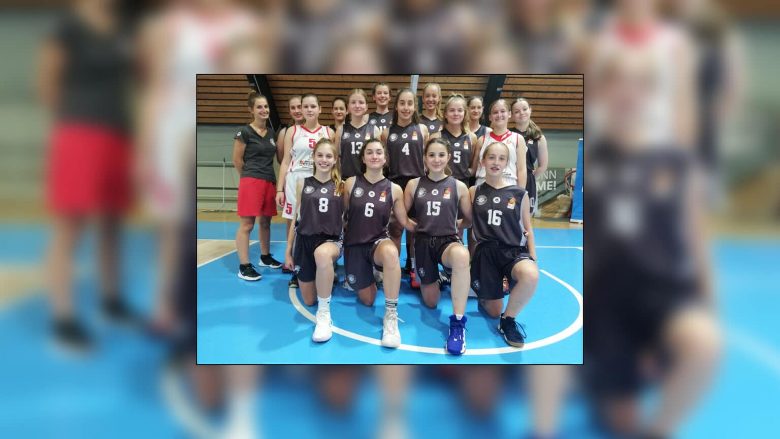 Jugendvolleyballmannschaft der RheinStars Köln in schwarzen Trikots posiert in einer Sporthalle.