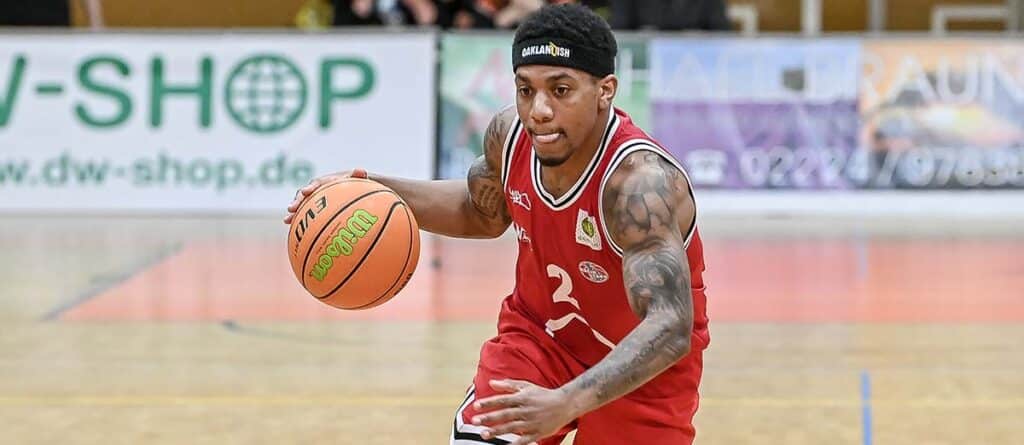 Basketballspieler der RheinStars Köln dribbelt in rotem Trikot mit Nummer 2.