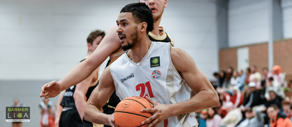 Basketballspieler der RheinStars Köln mit Nummer 21 hält Ball während Spiel.