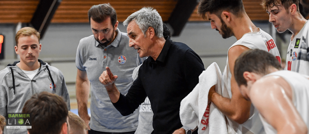 Coach der RheinStars Köln gibt Anweisungen an seine Spieler in der Halle.