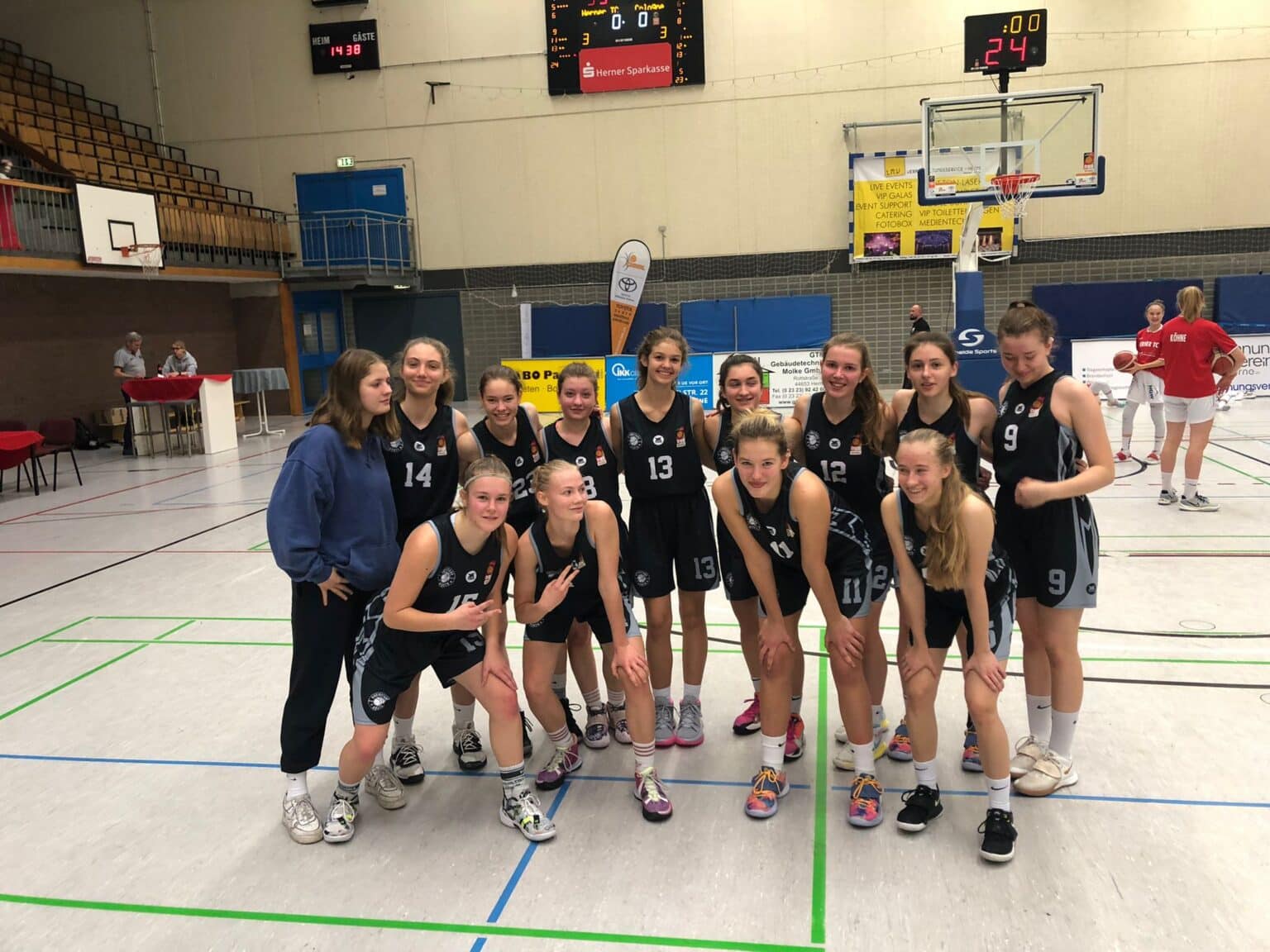 Damenvolleyballteam der RheinStars Köln posiert geschlossen in der Sporthalle.